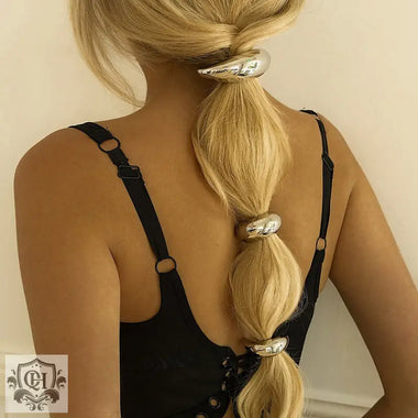 Blonde hair styled in a bubble ponytail with 18K gold U-shaped design hair accessory