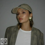 Woman in a blazer and baseball cap showcasing 18K gold rectangular design earrings