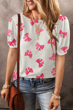 White blouse with pink bow prints and puff sleeves paired with blue jeans for relaxed style