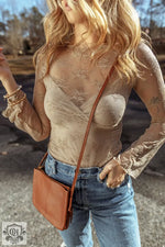 Sheer beige lace bodysuit styled with blue jeans and brown crossbody bag for relaxed look