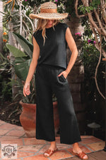 Woman in black quilted lounge set featuring textured knit cap sleeve T-shirt and wide leg pants