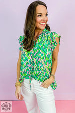 Woman wearing a green abstract print ruffled trim tied split neck tank top