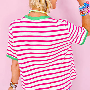 Pink and white striped crew neck top paired with jeans and a green cap for a relaxed look