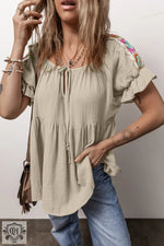 Beige peasant blouse with colorful embroidery, ruffled sleeves, and sizes for a relaxed fit