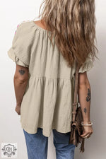 Beige tiered babydoll top with short puff sleeves styled with blue jeans in various sizes