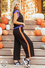 Woman in black and orange track suit highlighting the Strawberry Pink Color Block Detail