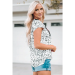 White blouse with black abstract pattern and denim shorts, perfect for relaxed styles